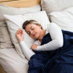 a woman sleeping on a bed with a blue blanket